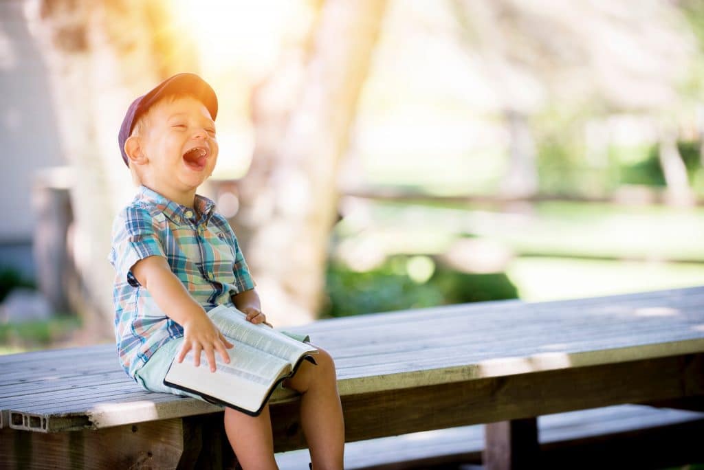 boy laughing holding book