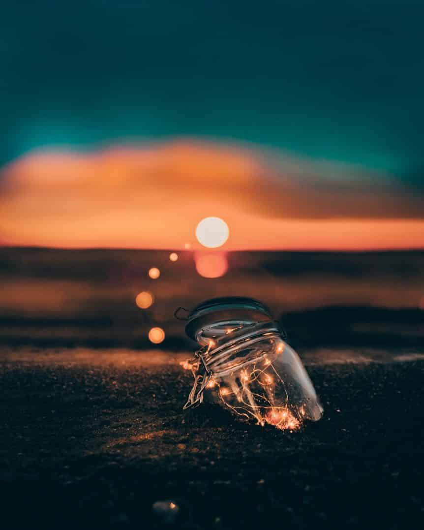 jar in sand with lights