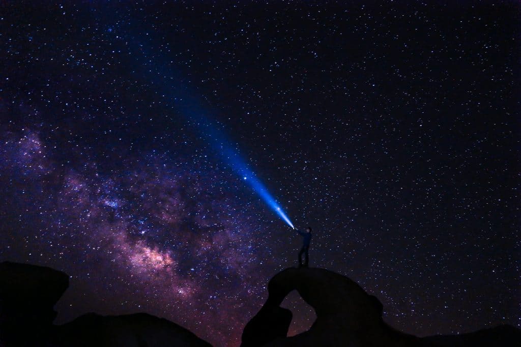 man shining light into night sky