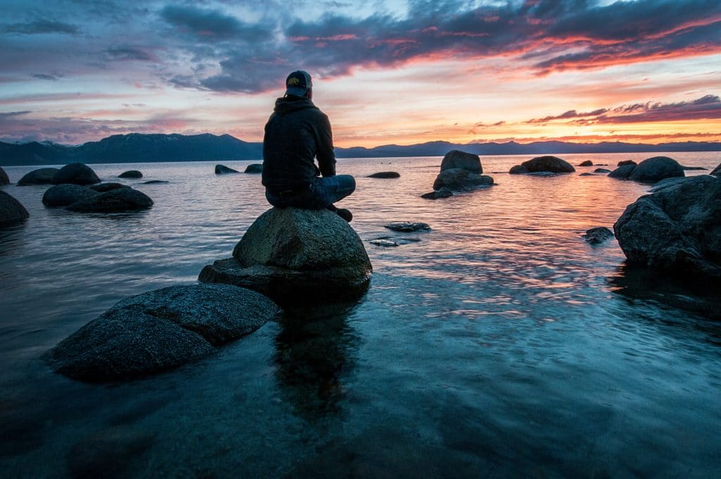 man sitting on rock in water